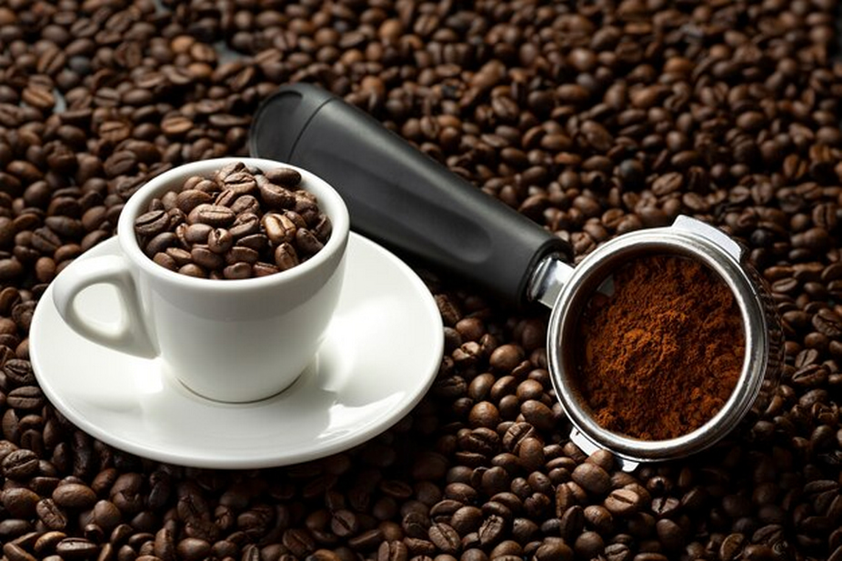 A cup filled with coffee beans and a scoop of ground coffee.